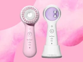 Two Clarisonic facial cleansing devices are artfully displayed against a pink backdrop. The left device boasts a pink hue with a circular brush head, while the right is elegantly white and lavender with intuitive button controls. Both models feature Daily Cleanse and Smart settings for personalized skincare.