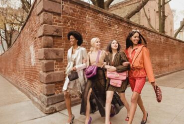 Four women stroll down the street, showcasing their stylish purses, embodying the essence of luxury fashion.