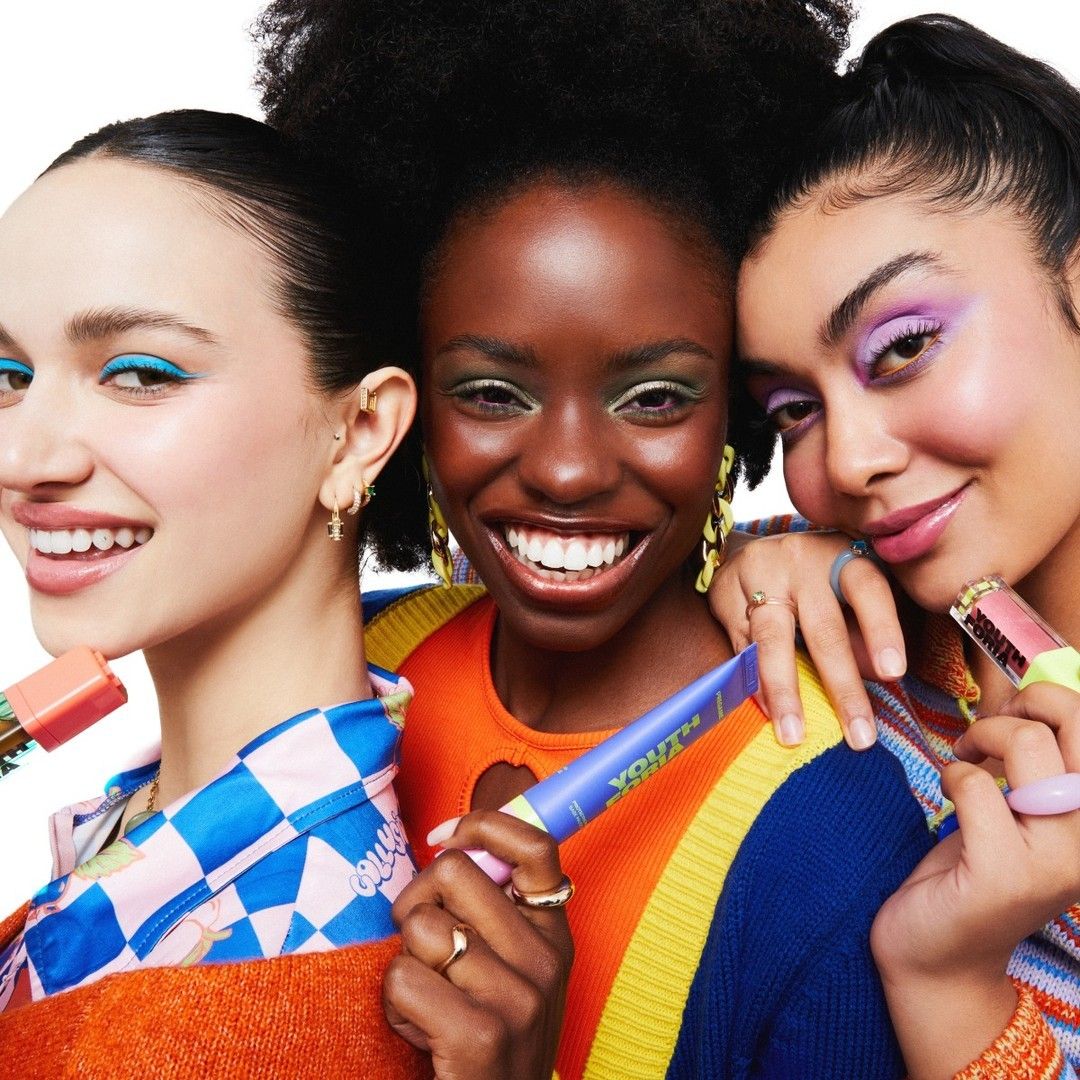 Three joyful women display their makeup brushes, showcasing the spirit of women-owned beauty brands.