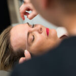 A woman is having her eyebrows styled by a man, highlighting essential eyebrow tips for achieving a refined appearance.