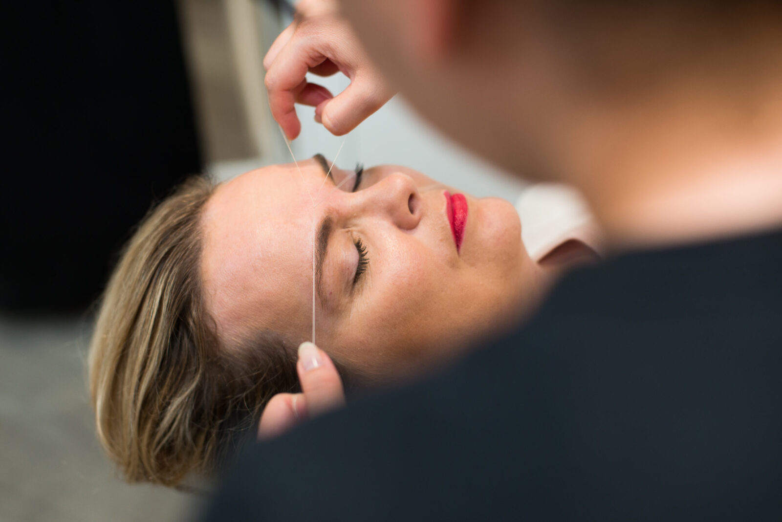A woman is having her eyebrows styled by a man, highlighting essential eyebrow tips for achieving a refined appearance.