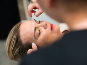 A woman is having her eyebrows styled by a man, highlighting essential eyebrow tips for achieving a refined appearance.
