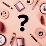 Various symbols on beauty products displayed alongside makeup brushes and eyeshadow, representing common labels found on cosmetic packaging.