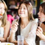 Three friends enjoying food together at a restaurant, sharing laughs and savoring delicious meals.