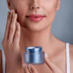 A woman gently applying moisturizing cream to her face, highlighting a skincare routine for glowing skin.